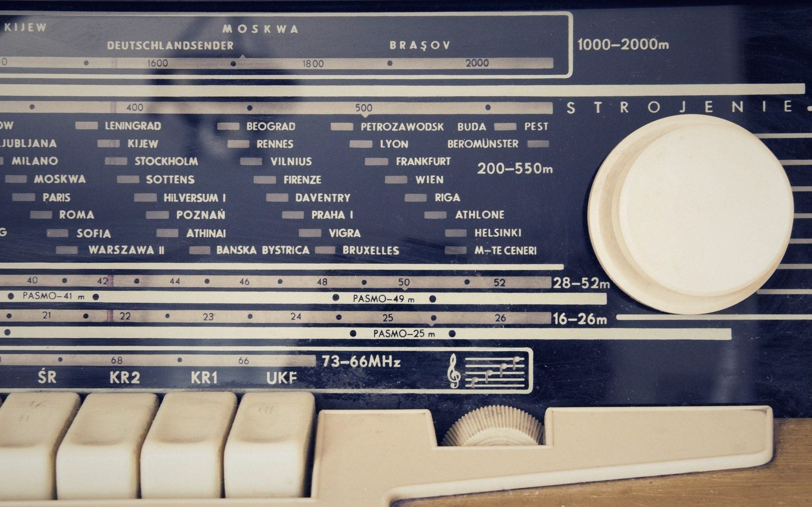 Vintage radio dial showing european city names, frequency bands, and tuning knob