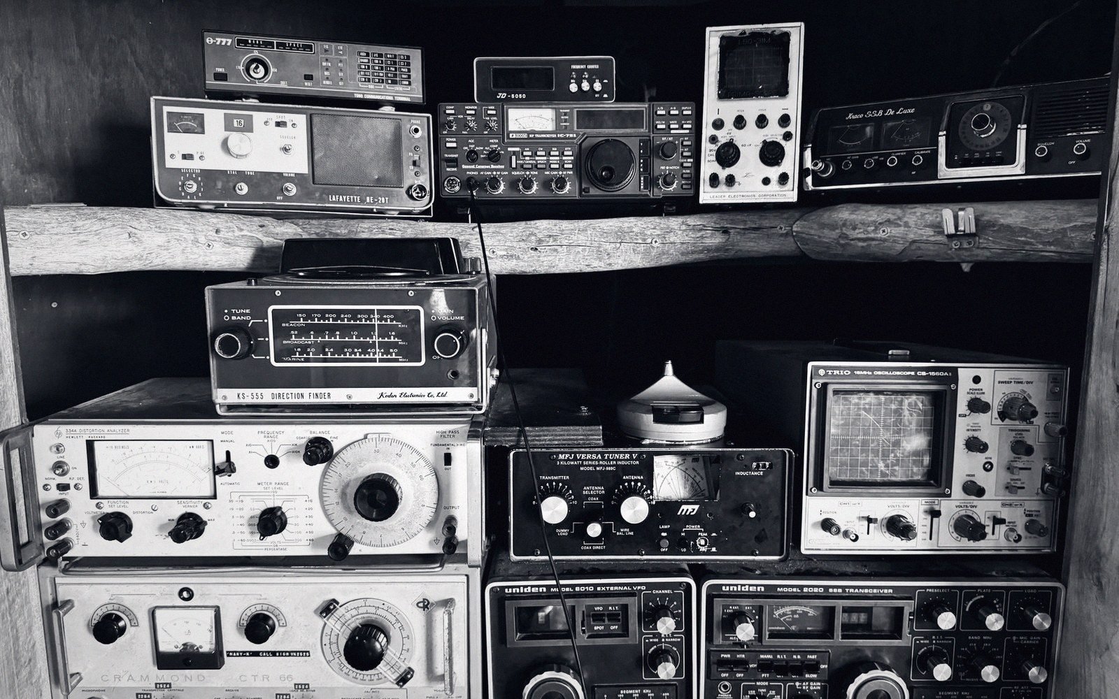 Shelves of vintage radio receivers, tuners and transceivers with analog dials and meters