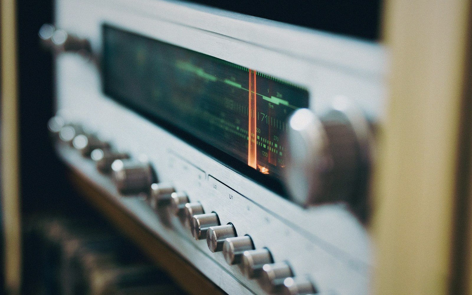 Close-up of a vintage radio tuner's illuminated glass dial and control knobs