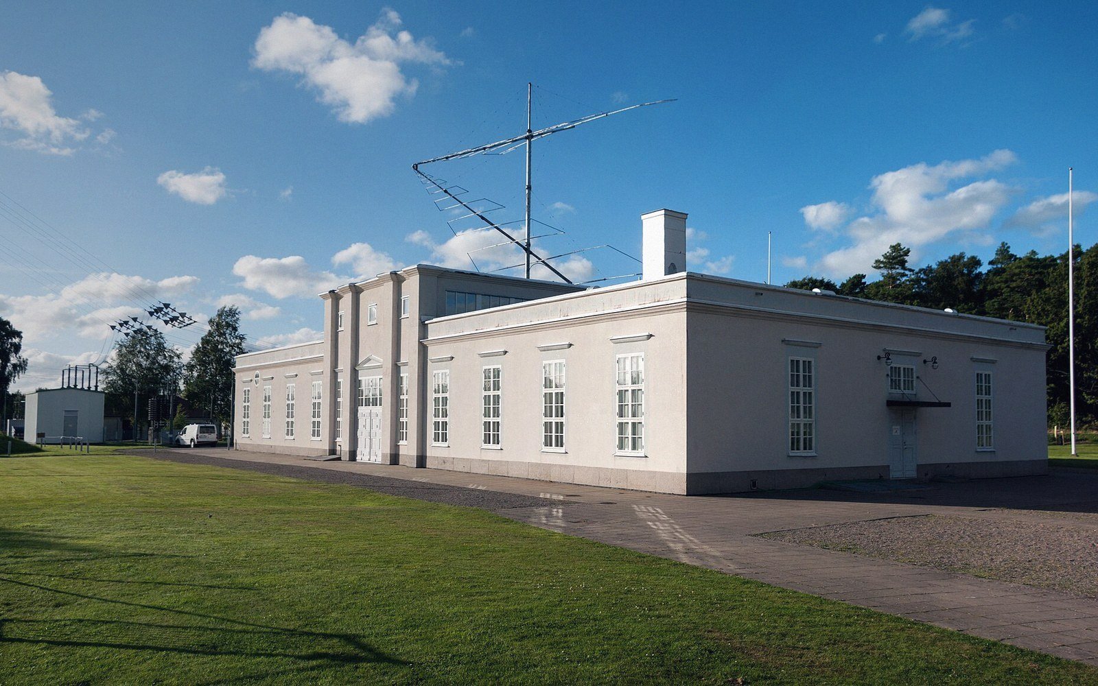Long white radio station building with a rooftop antenna mast under a blue sky